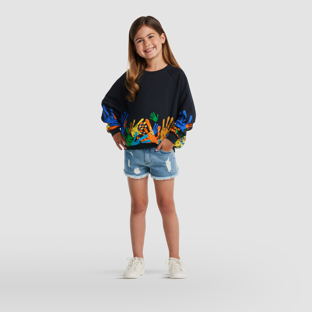 Girl wearing Global Unity Everyday Sweater and Distressed Cutt-off Short by BE.Kids
