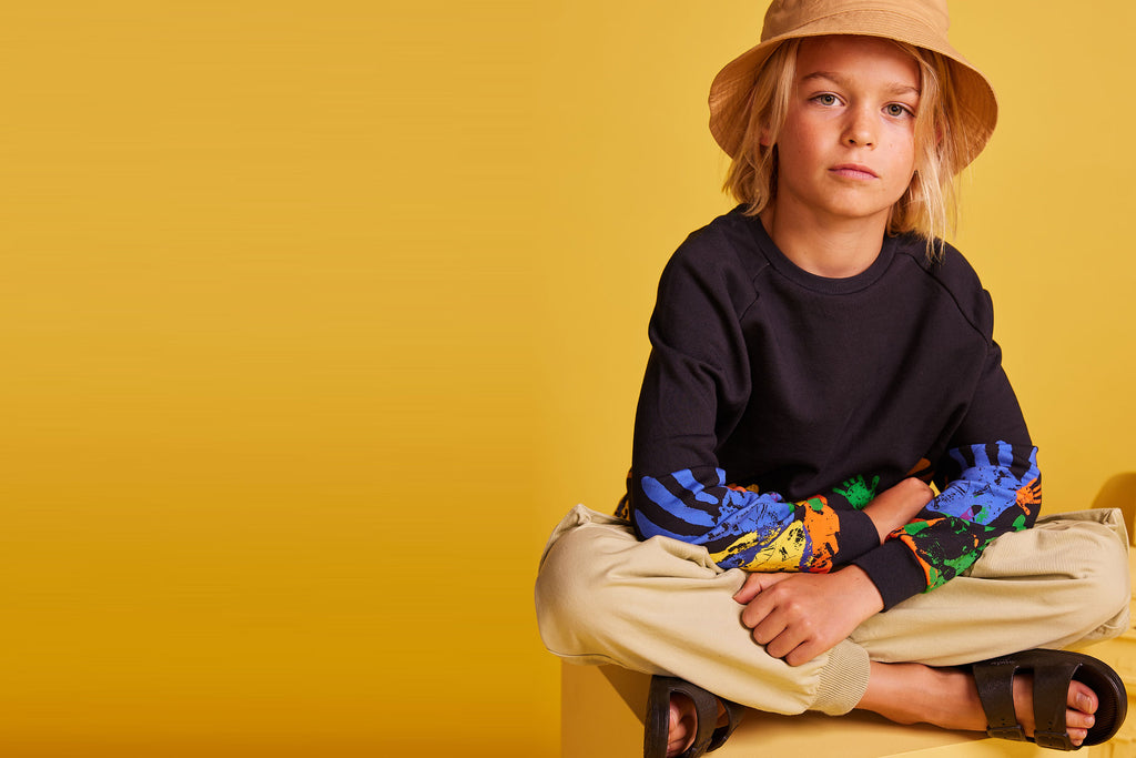 Boy in bucket hat wearing Global Unity Crewneck and Resilient Cargo Pants by BE.Kids